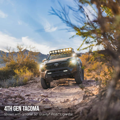 4th generation Toyota Tacoma driving on a dirt road with optional light bar, surrounded by desert landscape.