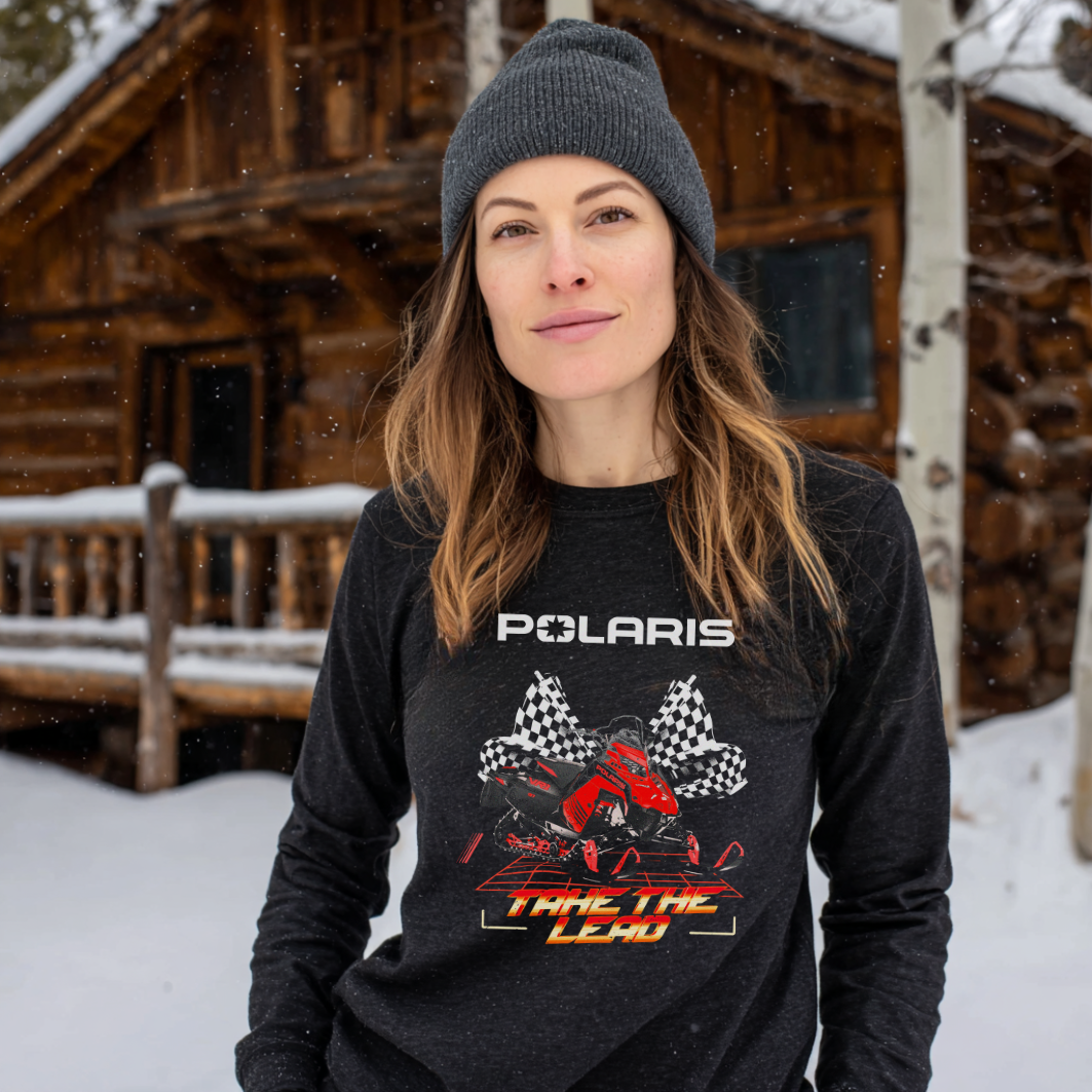 Woman wearing a Polaris shirt in front of a wooden cabin in the snow