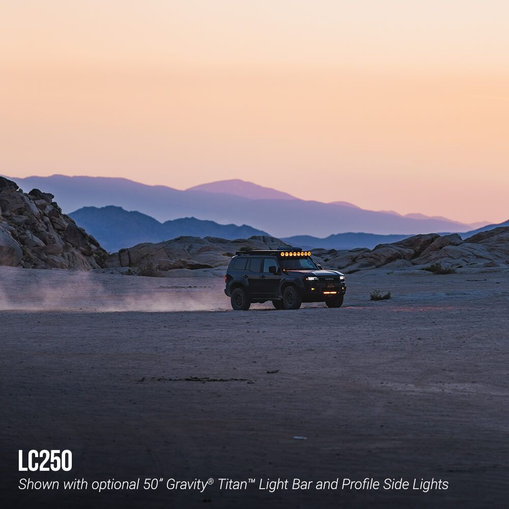 SUV in a desert landscape with mountains at sunset, featuring optional light bar and side lights.