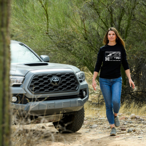 Woman walking on a dirt path with a Toyota truck in the background