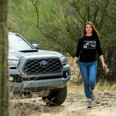 Woman walking on a dirt path with a Toyota truck in the background