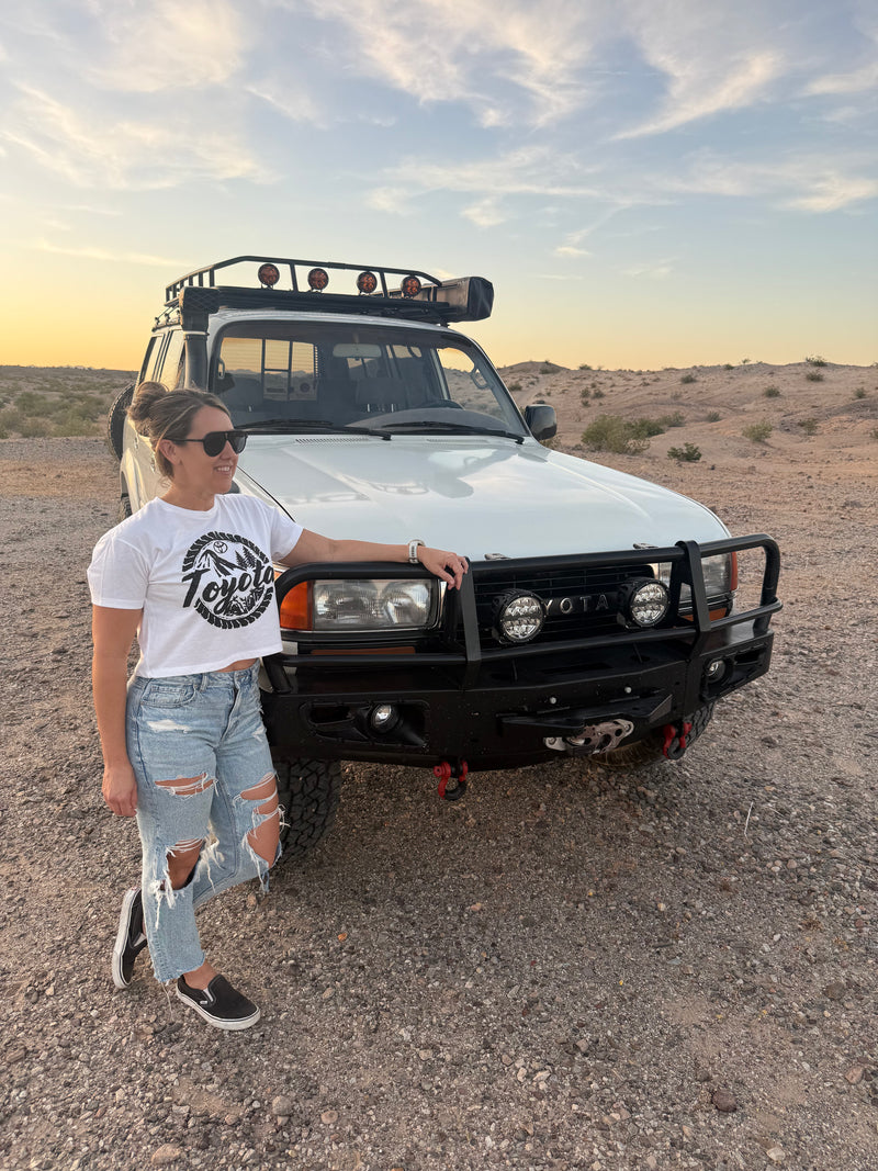 Person standing next to a white off-road vehicle in a desert landscape