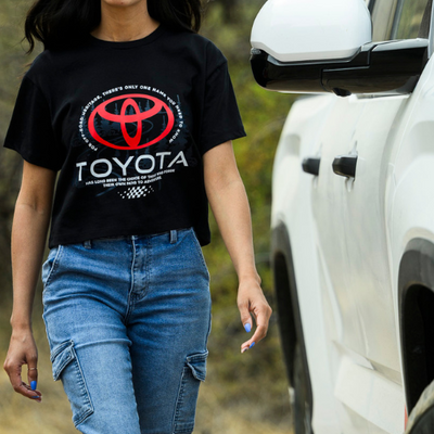 Person wearing a black Toyota t-shirt with a red logo, standing next to a white truck.