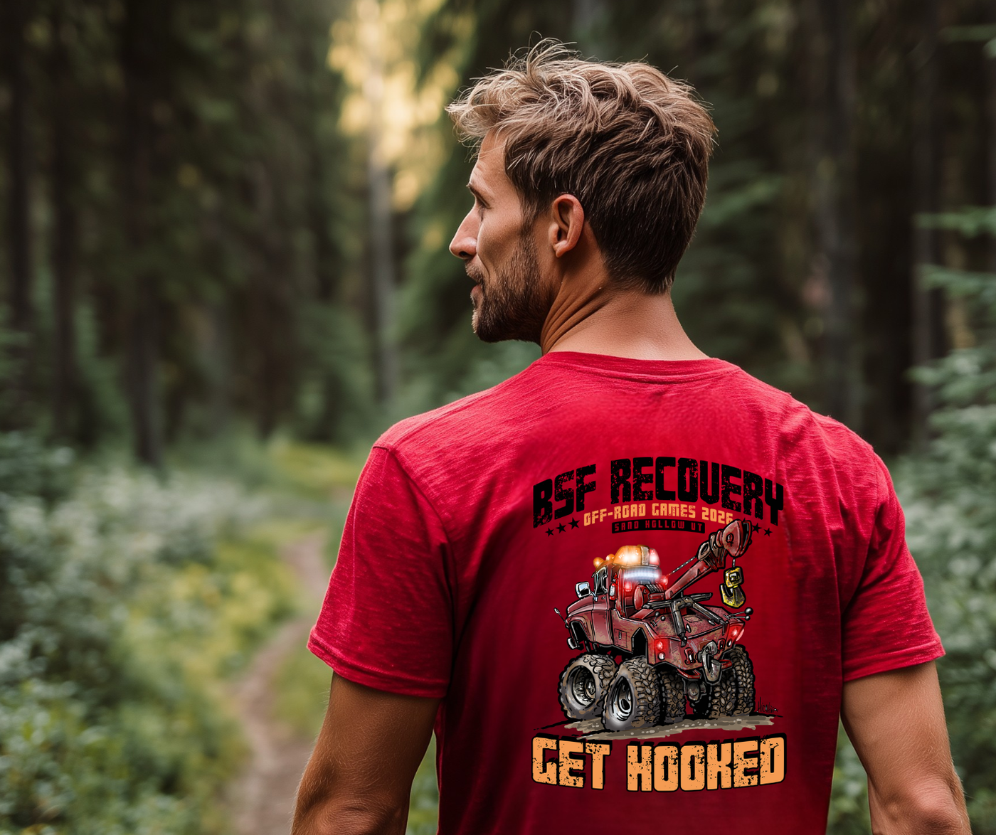 Man wearing a red t-shirt with off-road vehicle graphic and text in a forest setting