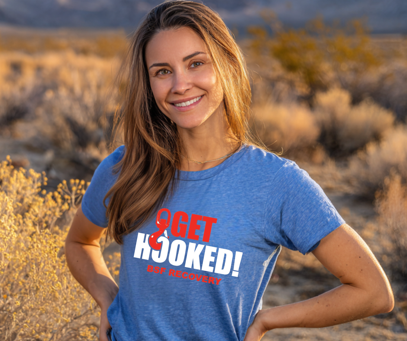 Woman wearing a blue t-shirt with '9GET HOOKED! Outdoors' text in a desert setting
