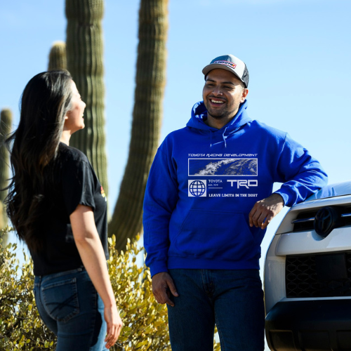 Two people standing next to a truck with cacti in the background