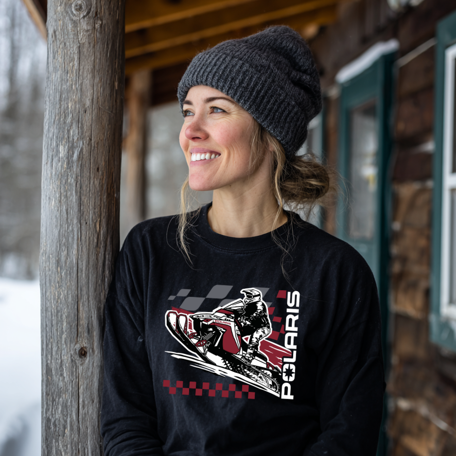 Woman wearing a black sweatshirt with Polaris logo in front of a wooden cabin.
