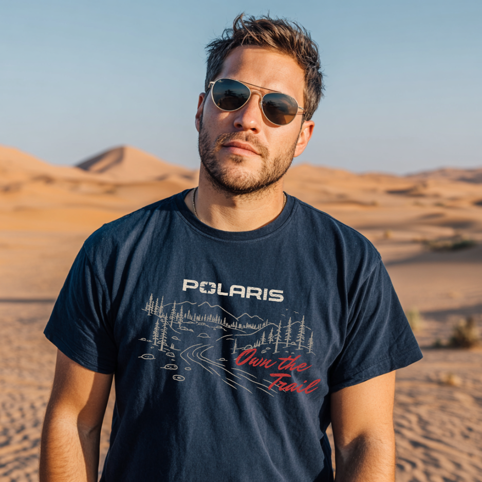 Man wearing a navy blue t-shirt with Polaris logo and text in a desert setting