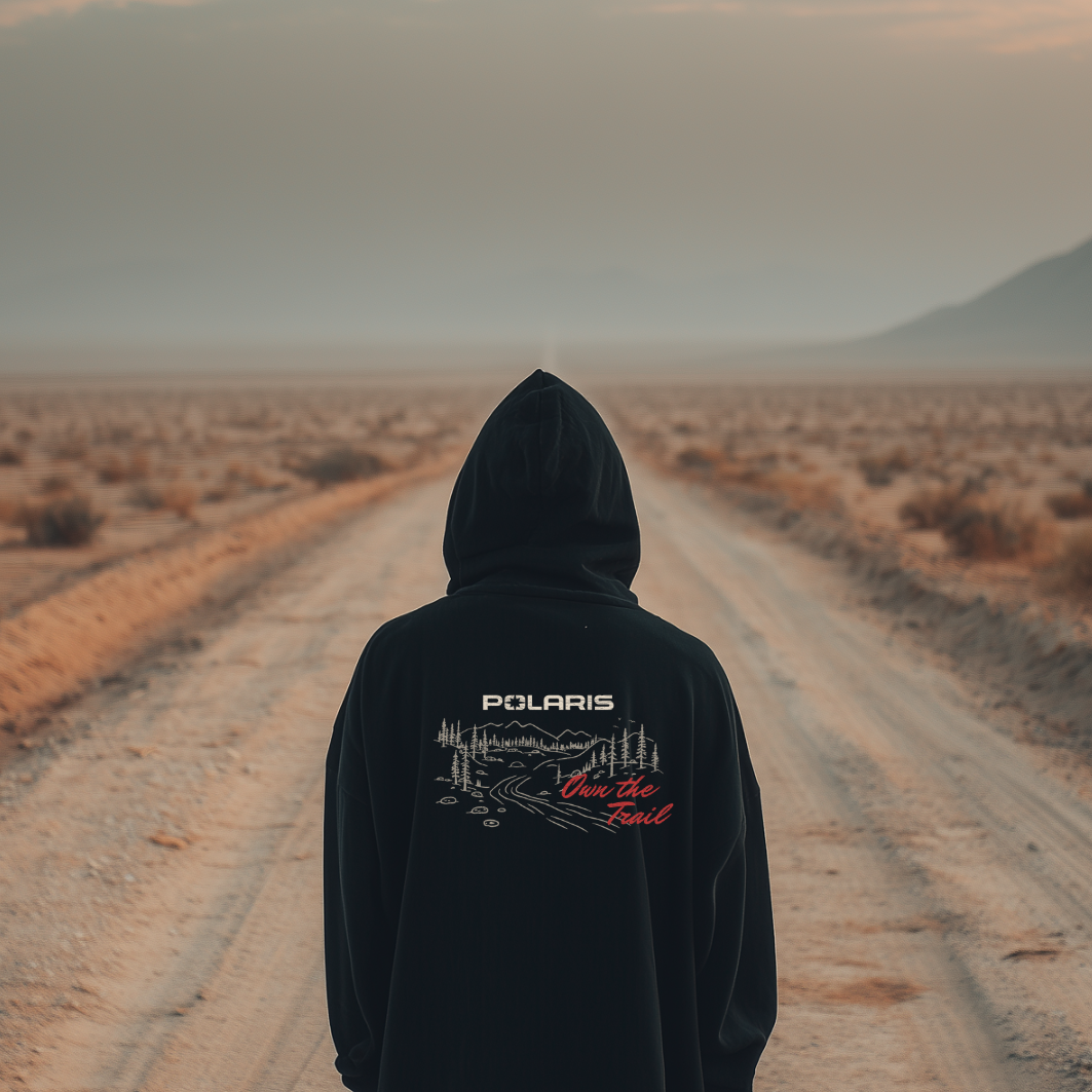 Person wearing a black hoodie with Polaris logo in a desert landscape