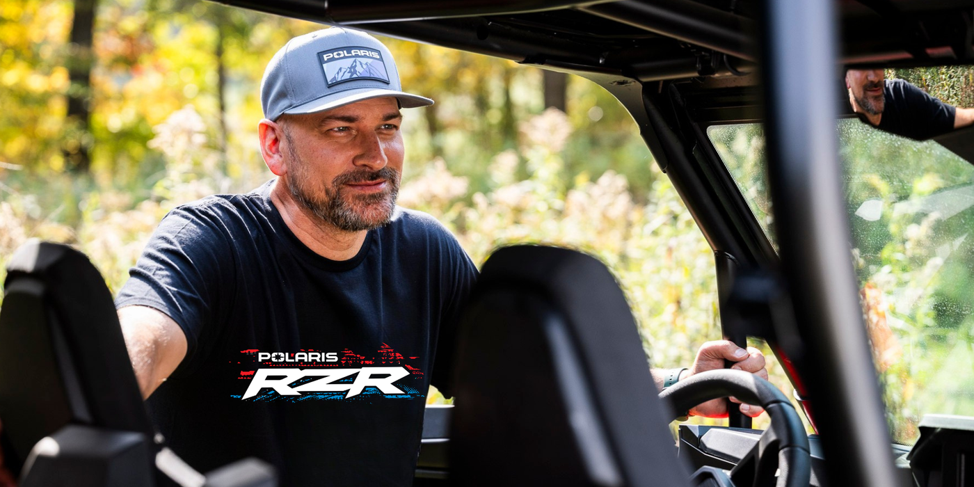 Man sitting inside a Polaris vehicle with a blurred natural background
