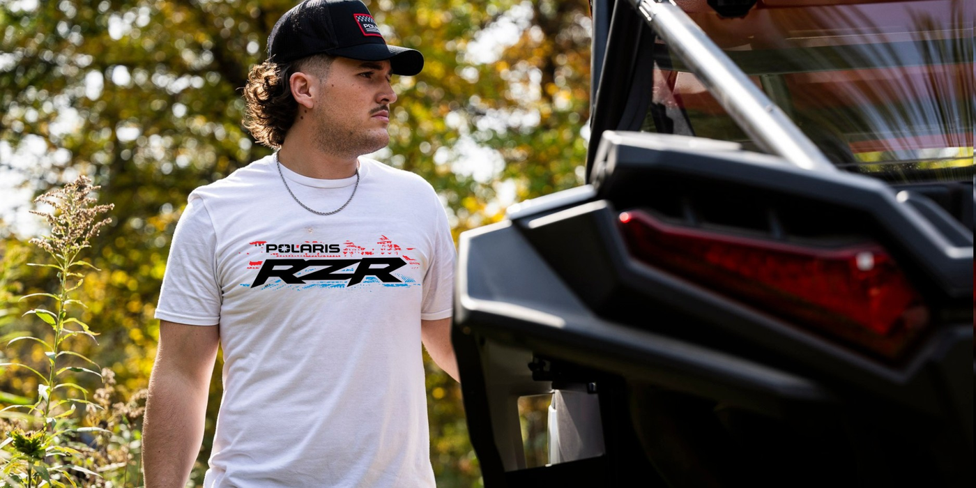 Man wearing a Polaris RZR shirt standing next to a vehicle with a blurred background