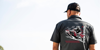 Person wearing a black Polaris shirt with a snowmobile graphic on the back.