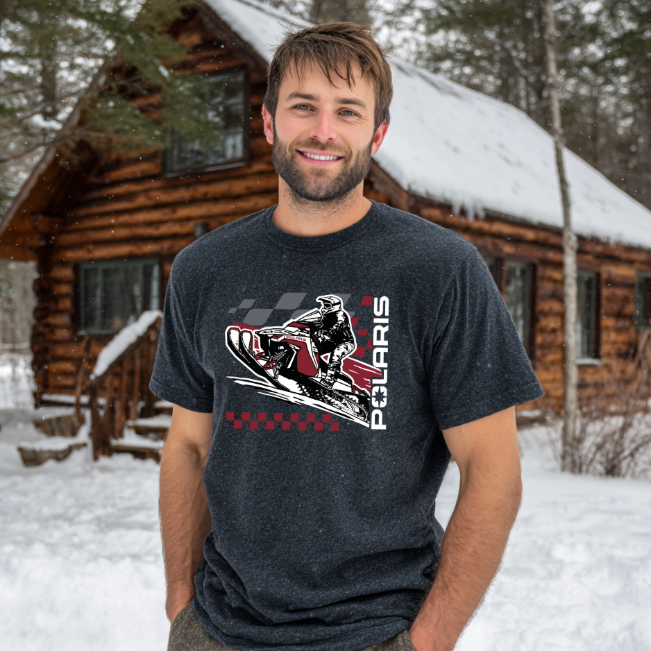 Man wearing a t-shirt with a Polaris graphic in front of a snow-covered cabin.