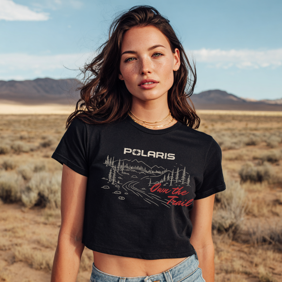 Woman wearing a black t-shirt with Polaris logo and text in a desert setting