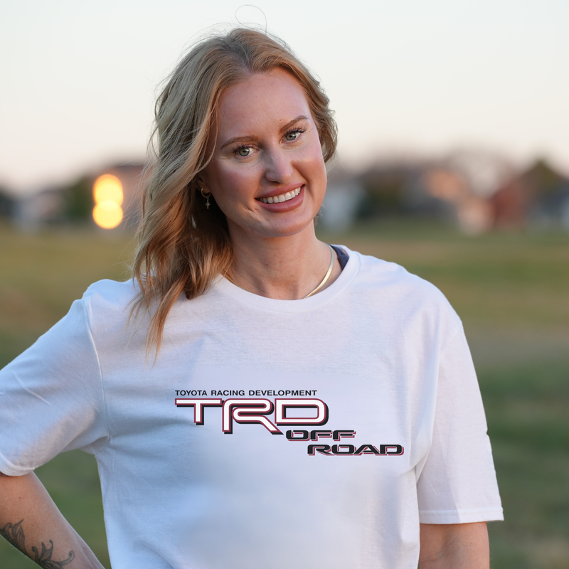 A smiling blonde woman wearing a white crewneck t-shirt with a &