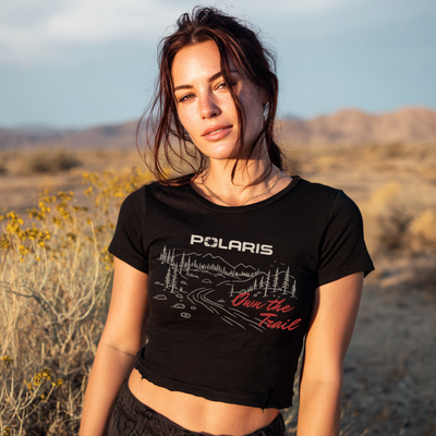 Woman wearing a black t-shirt with Polaris logo and text in a desert setting